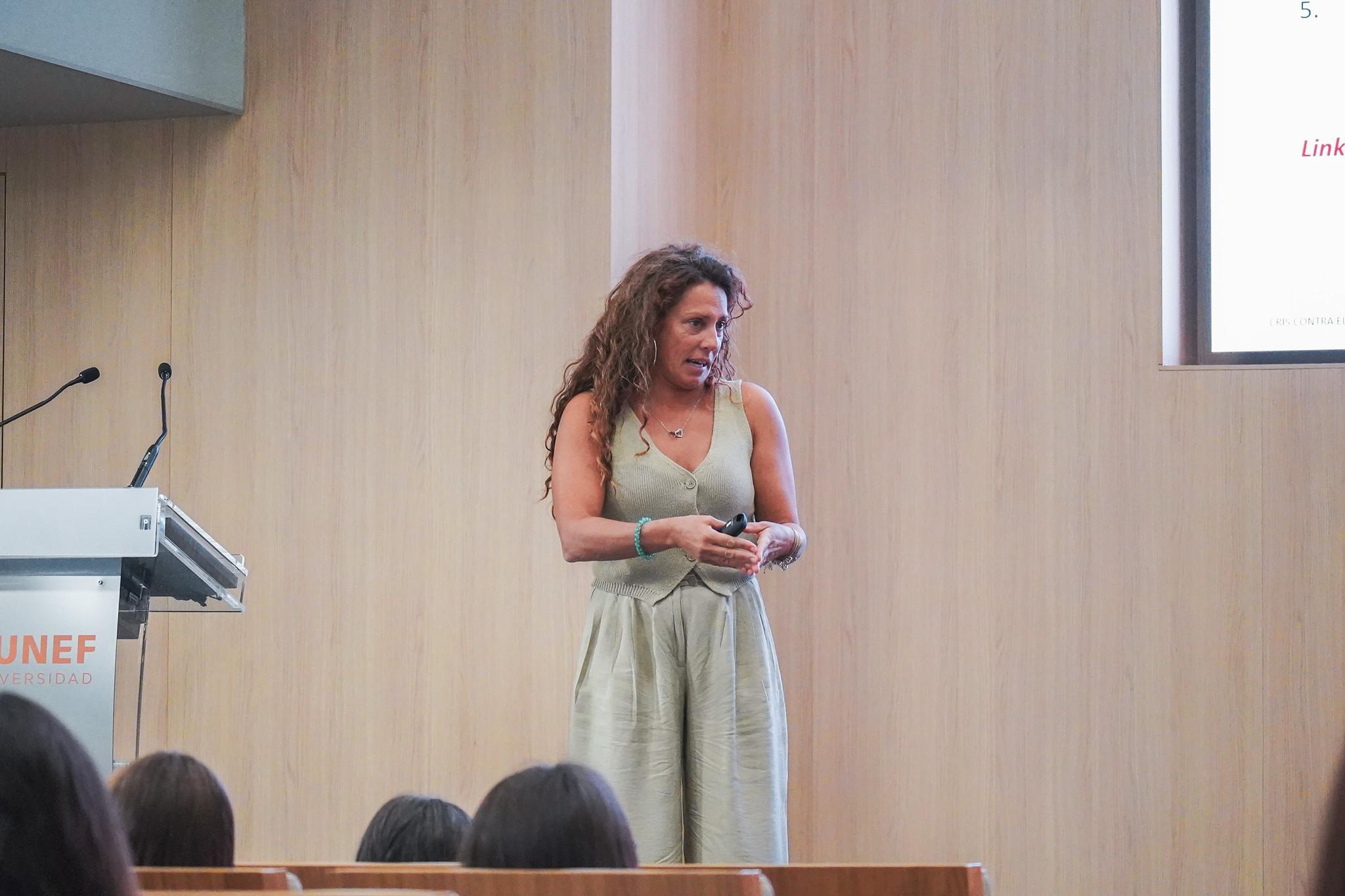 Una mujer con cabello rizado presenta en un auditorio.