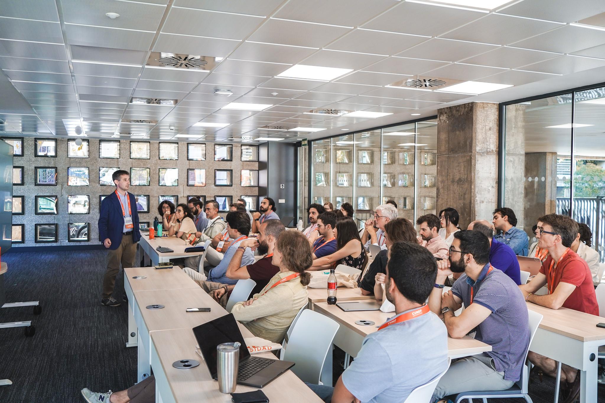 Un grupo de personas asiste a una presentación en un aula moderna.