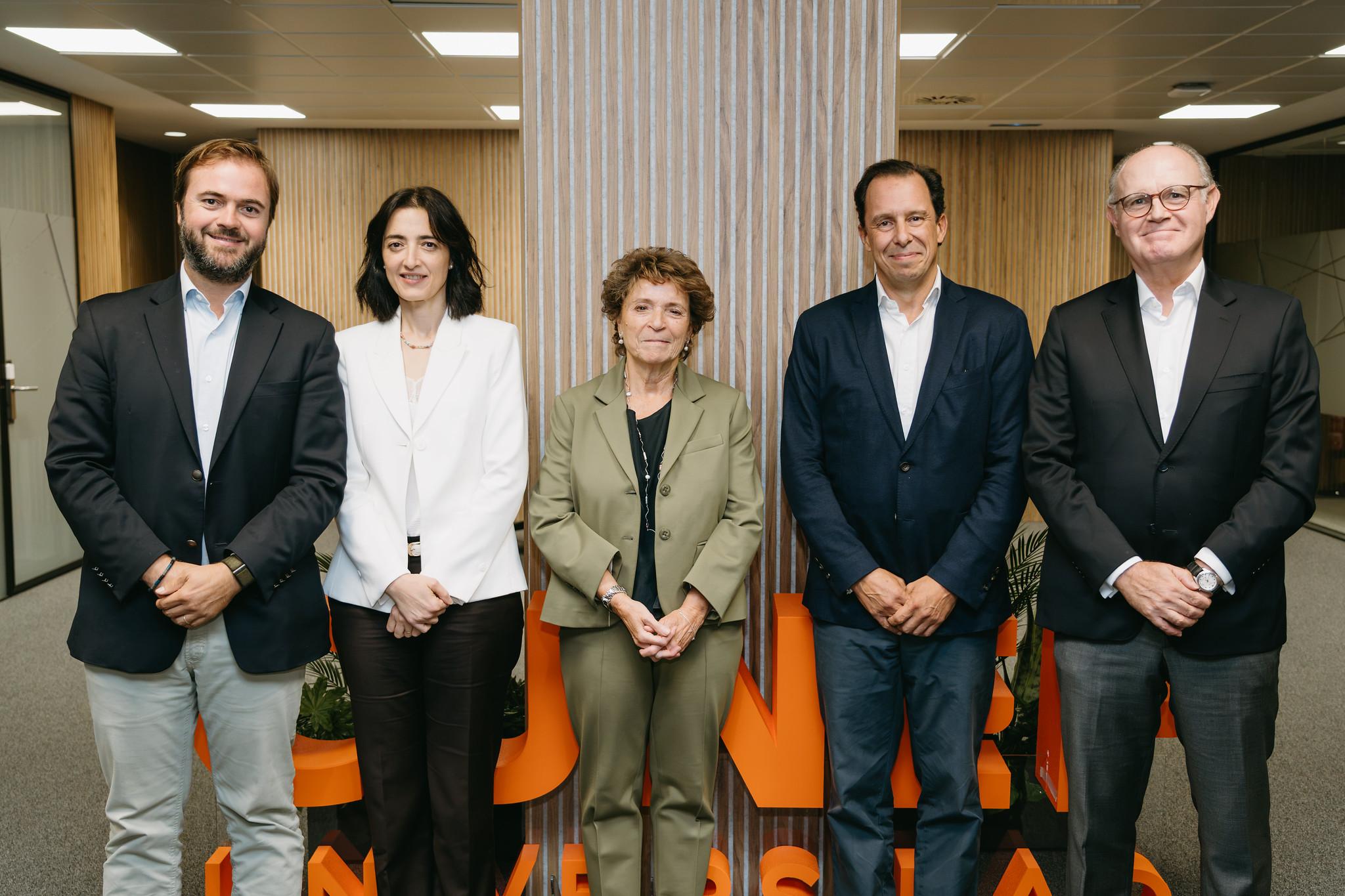 Un grupo de cinco personas posando en un entorno de oficina moderno.