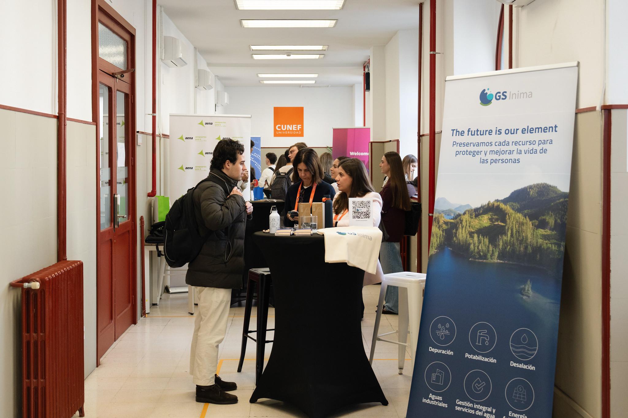 Una feria o evento con varios stands donde los participantes interactúan y recogen información.