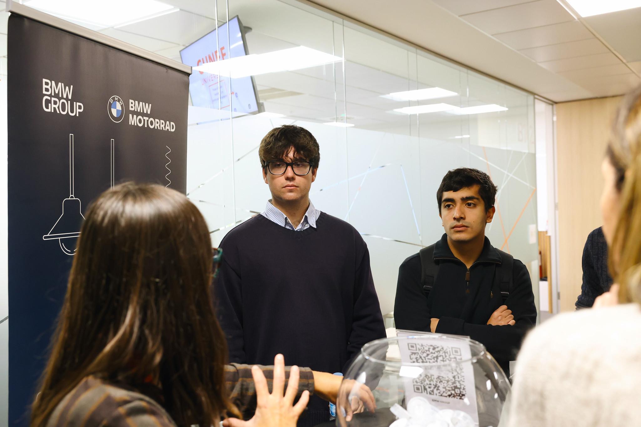 Un grupo de jóvenes escucha a una presentadora en un evento de BMW.