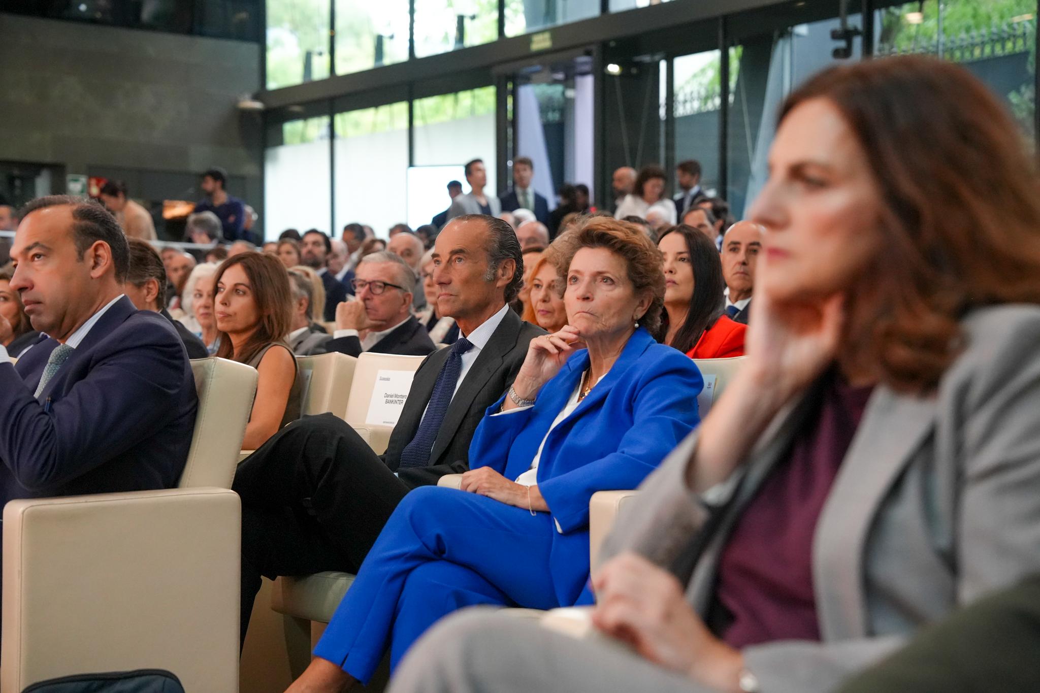 Un grupo de personas observando atentamente un evento en un auditorio moderno.