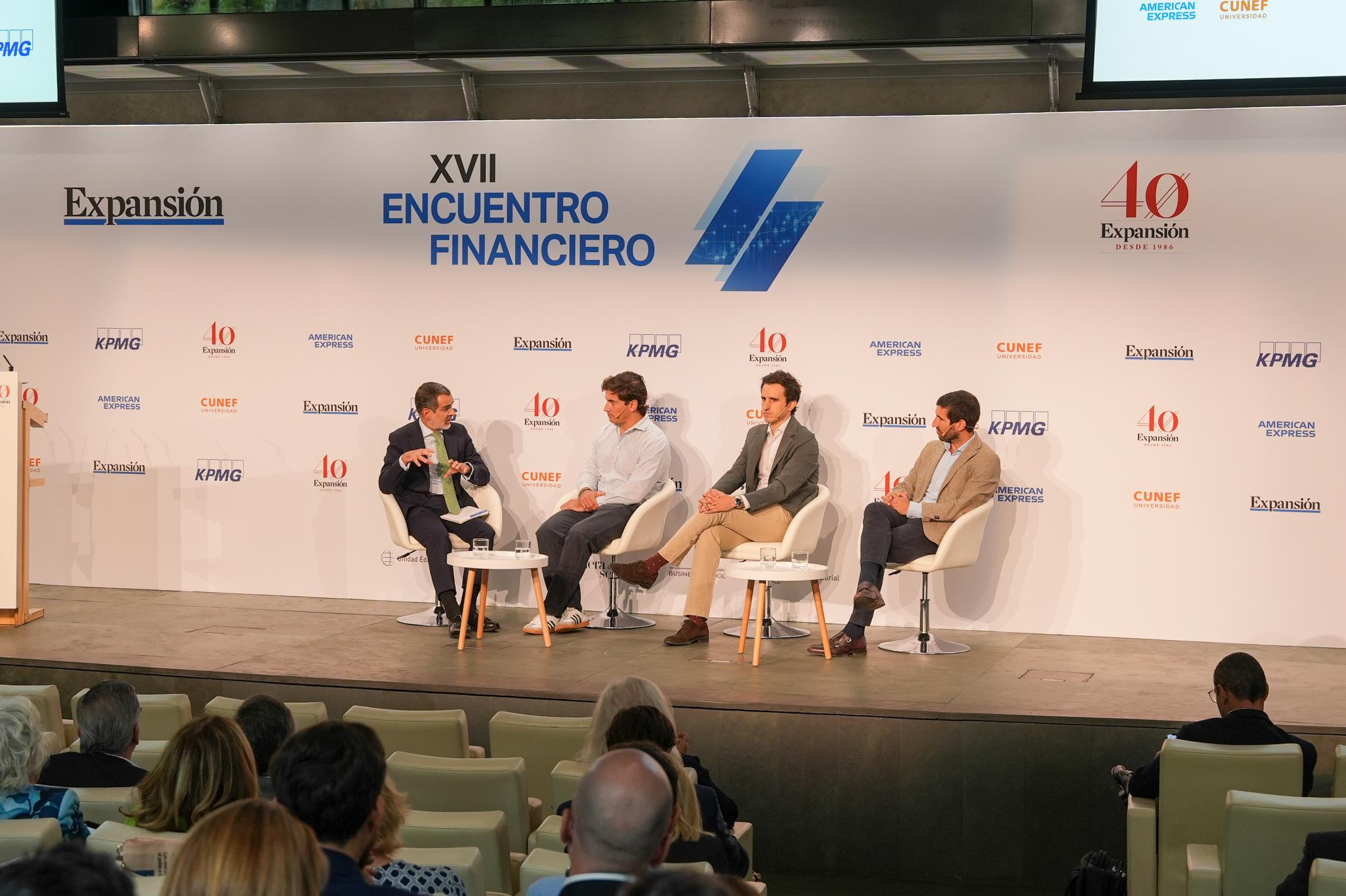 Un panel de discusión en un evento financiero con varios ponentes en el escenario.