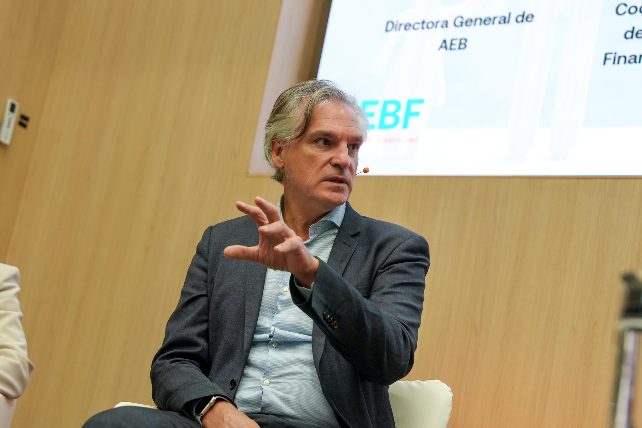 Un hombre sentado en un panel de discusión durante un evento empresarial.