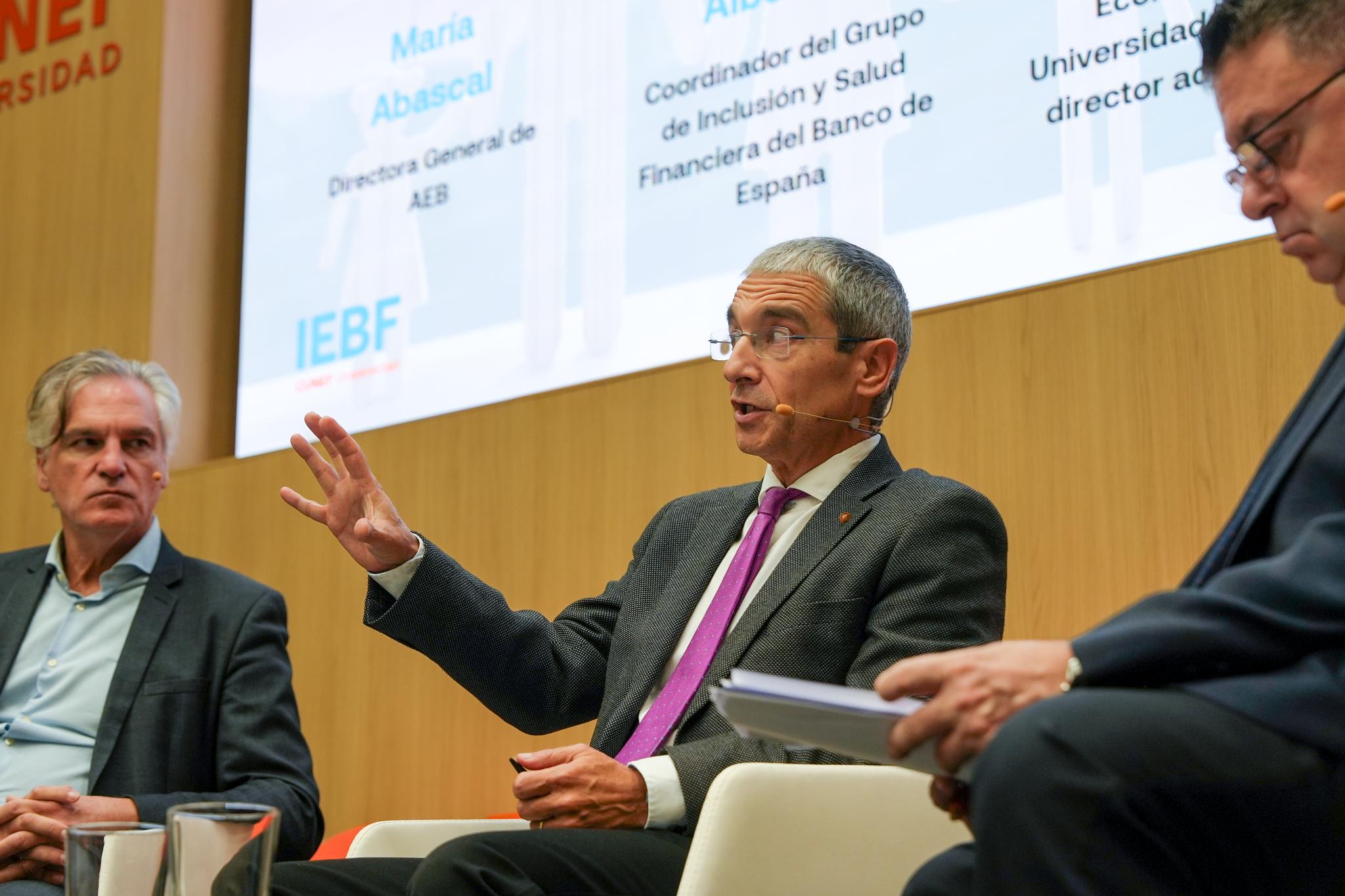 Una mesa redonda con tres ponentes discutiendo temas relacionados con la inclusión financiera en un evento académico.