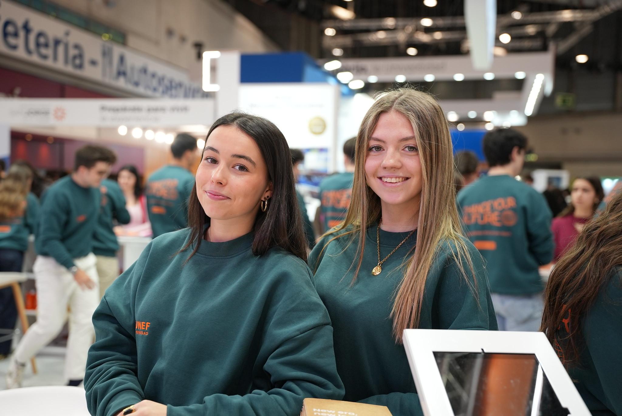 Dos jóvenes posan sonrientes en un evento con ropa personalizada.