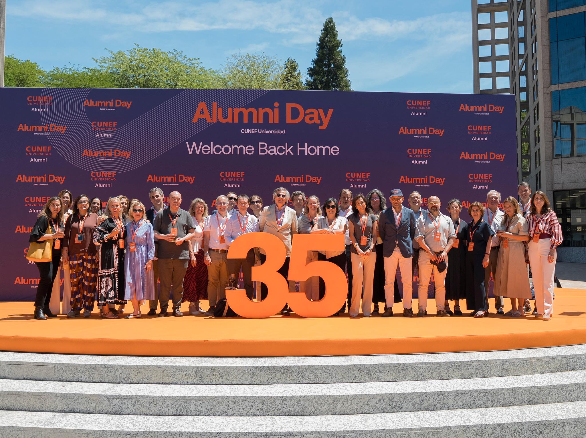Un grupo de personas se reúne para celebrar el Alumni Day en un evento festivo al aire libre.