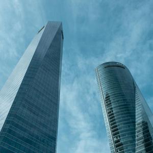 Dos rascacielos modernos se alzan contra un cielo azul con nubes.