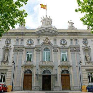 Edificio monumental con una fachada clásica y un mástil donde ondea la bandera de España.