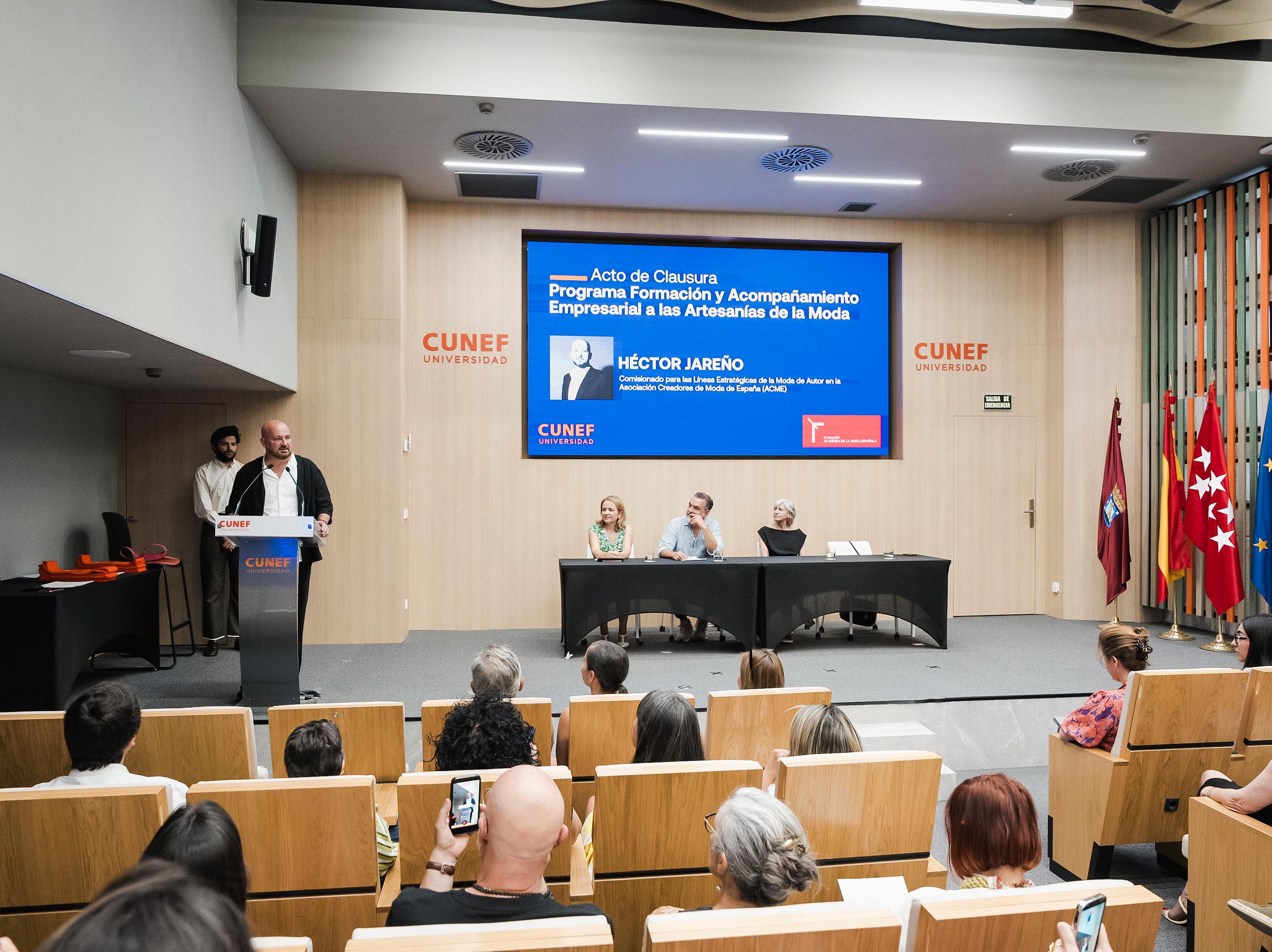 Una presentación en un acto de clausura de un programa relacionado con la moda en un auditorio.