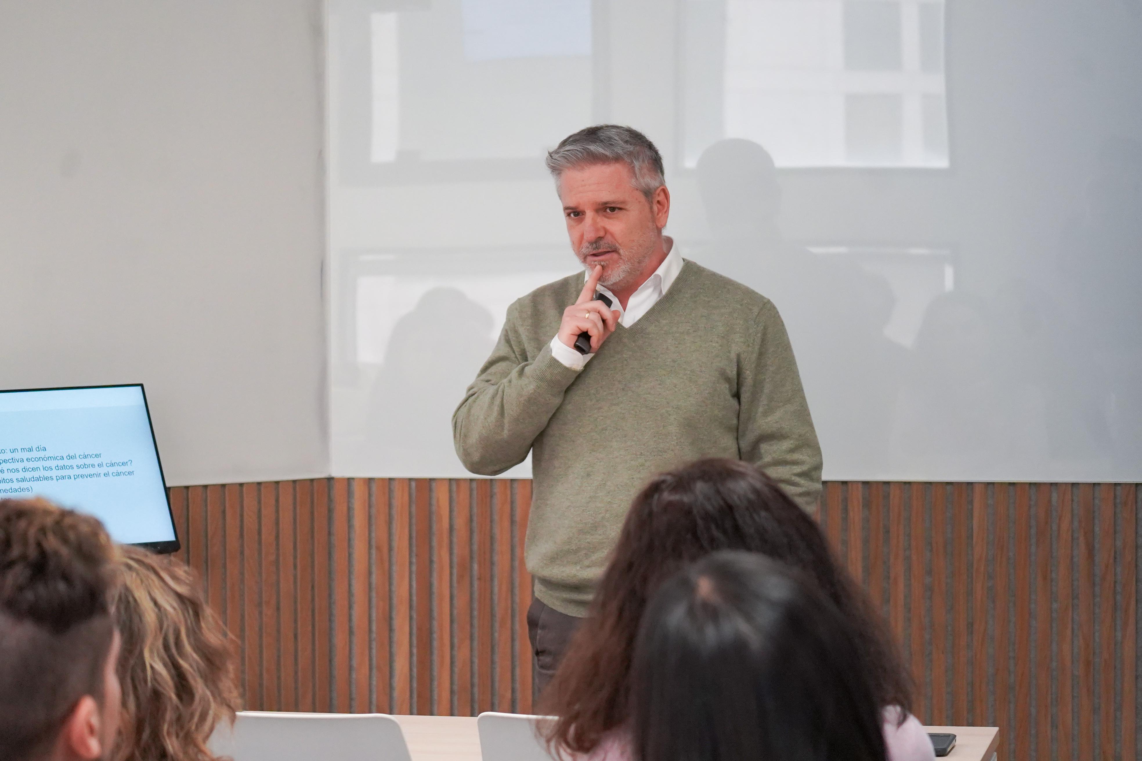 Un hombre está hablando frente a un grupo de personas en un ambiente de presentación.