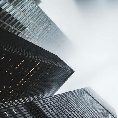 La imagen muestra edificios modernos rodeados de niebla con una perspectiva desde abajo hacia arriba.
