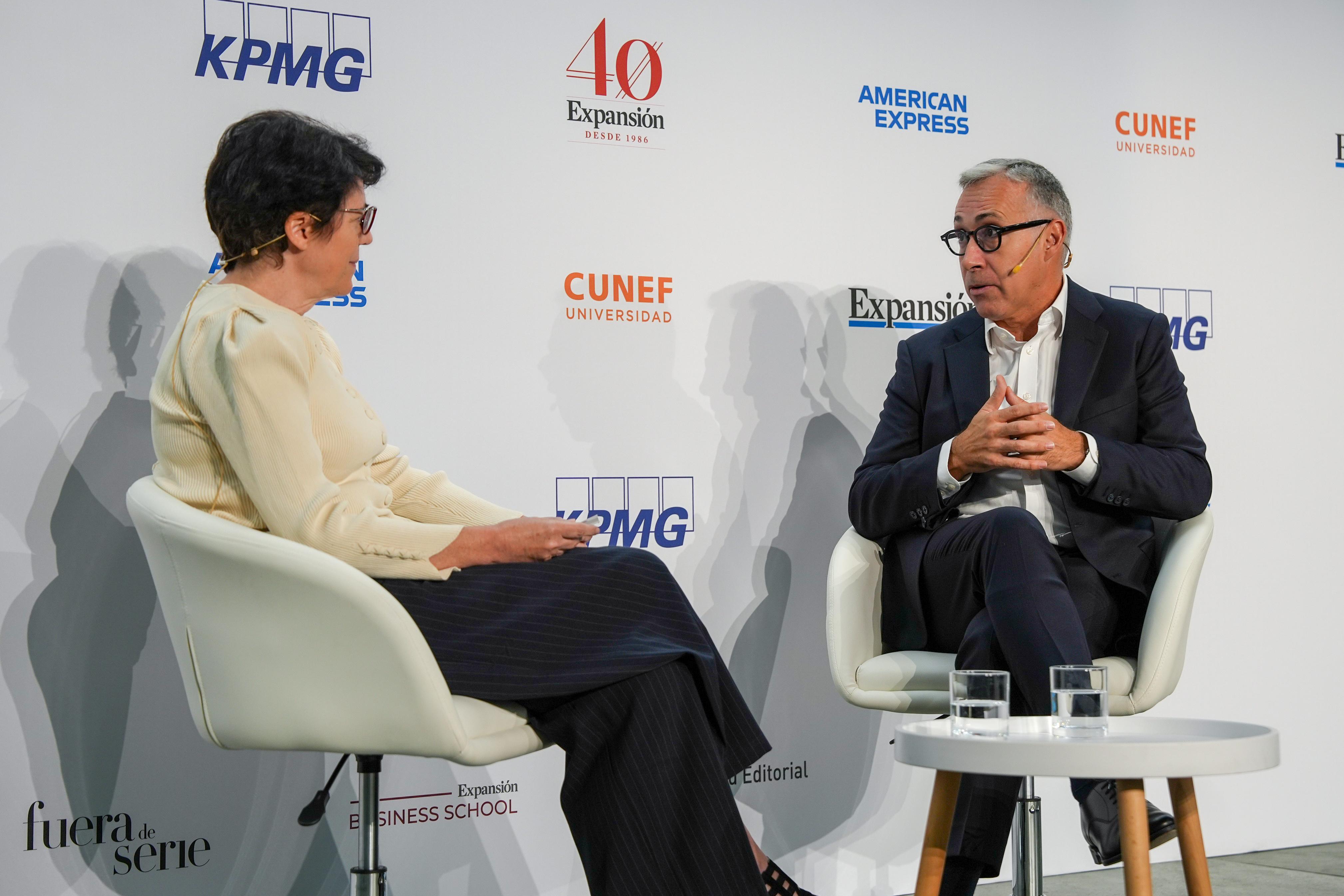 Una mujer y un hombre están sentados en sillas hablando durante un evento empresarial.