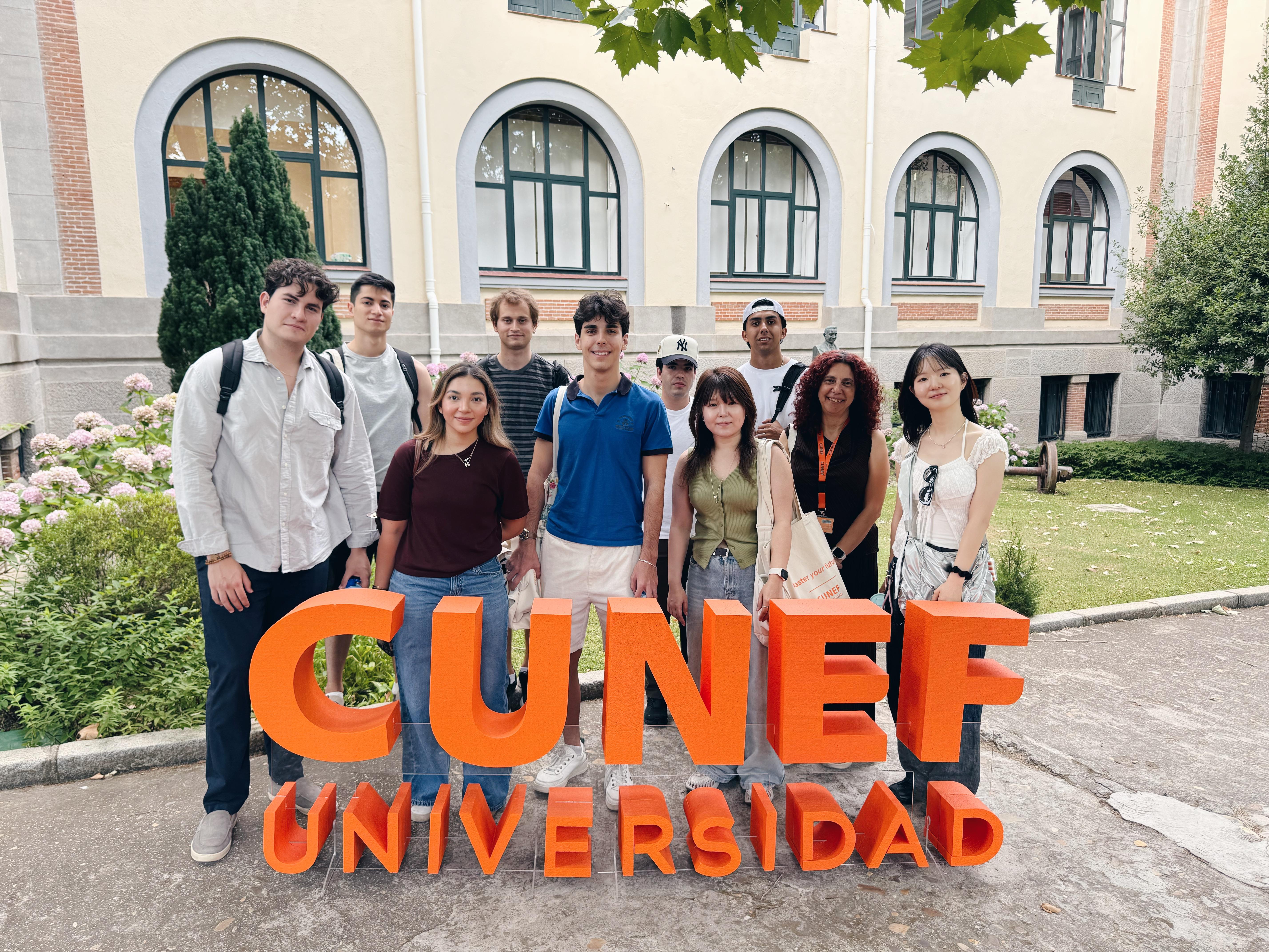 Un grupo de estudiantes posando frente al cartel de la Universidad CUNEF.