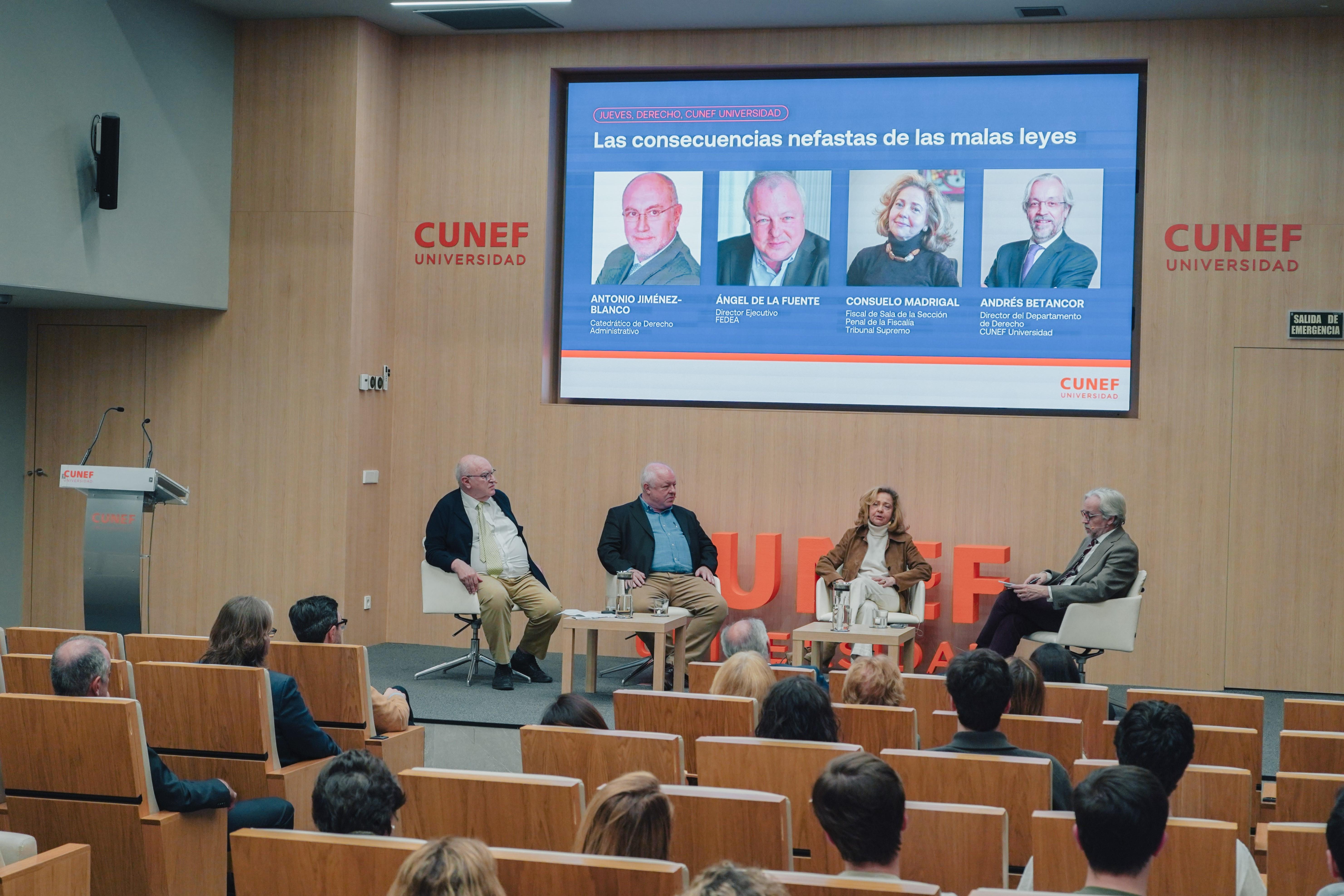 Un panel de discusión en la Universidad CUNEF sobre las consecuencias de las malas leyes, con varios ponentes en un auditorio lleno de público.