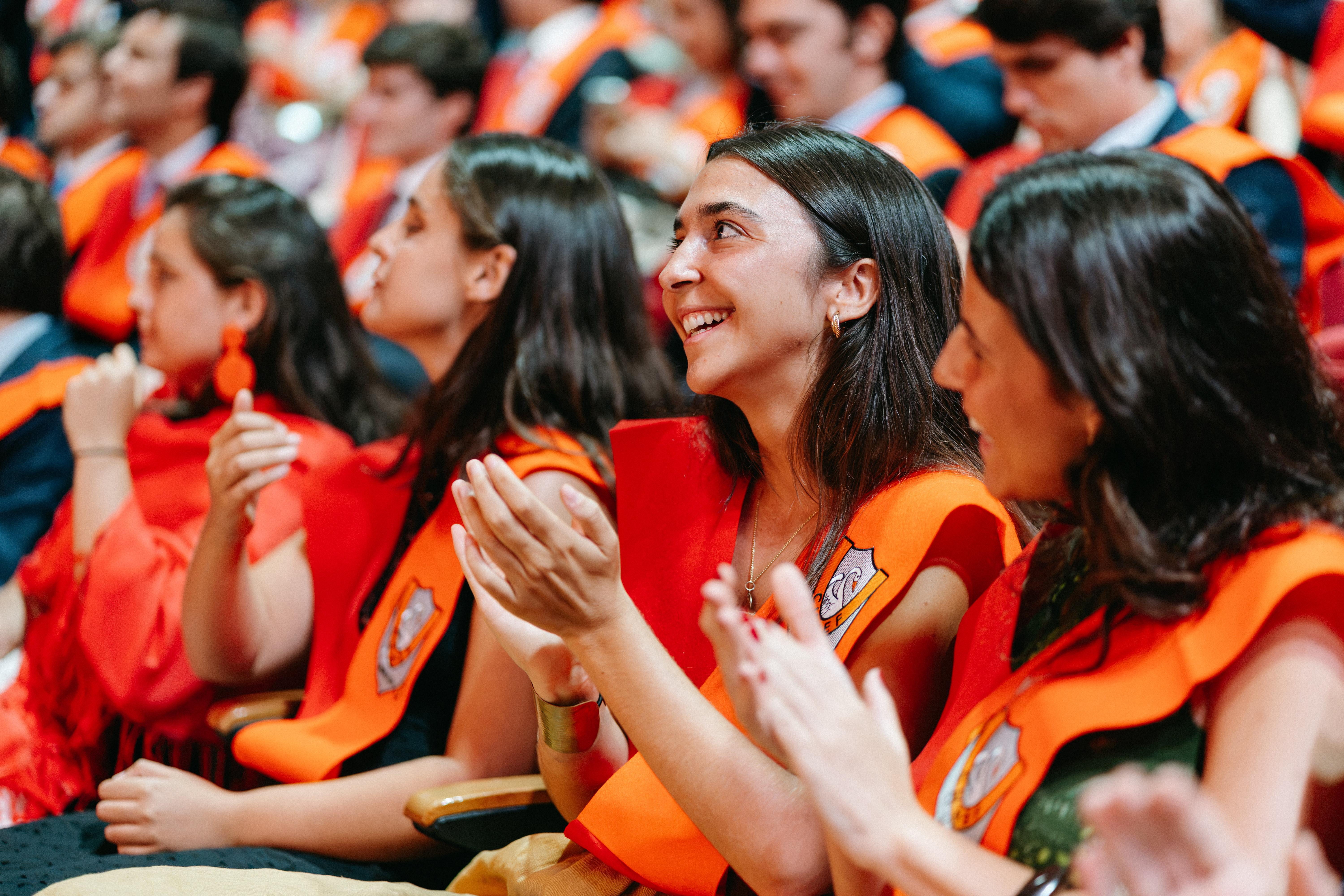 Un grupo de graduados celebra con sonrisas y aplausos en una ceremonia.