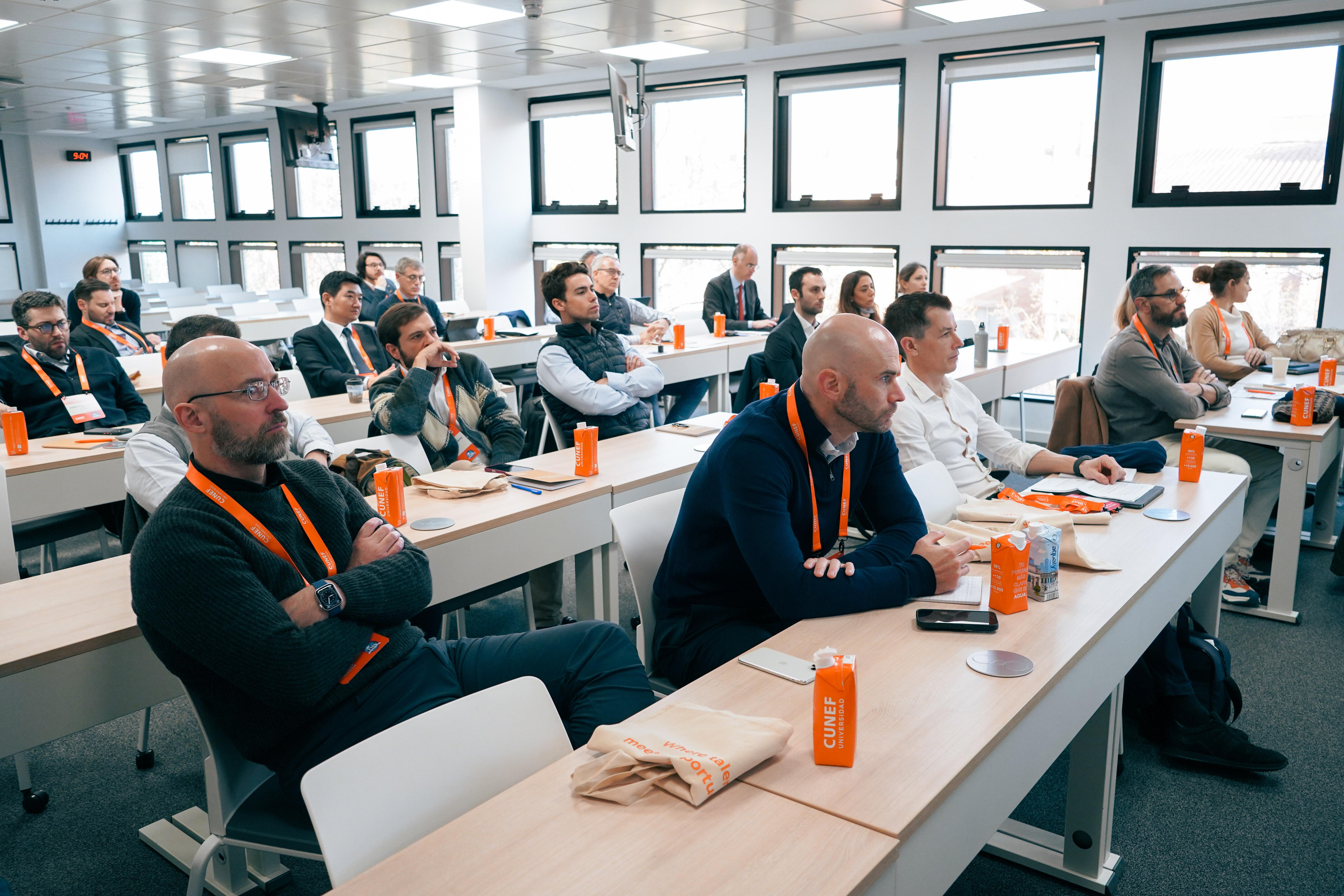 Una sala de conferencias con personas sentadas, prestando atención a una presentación.