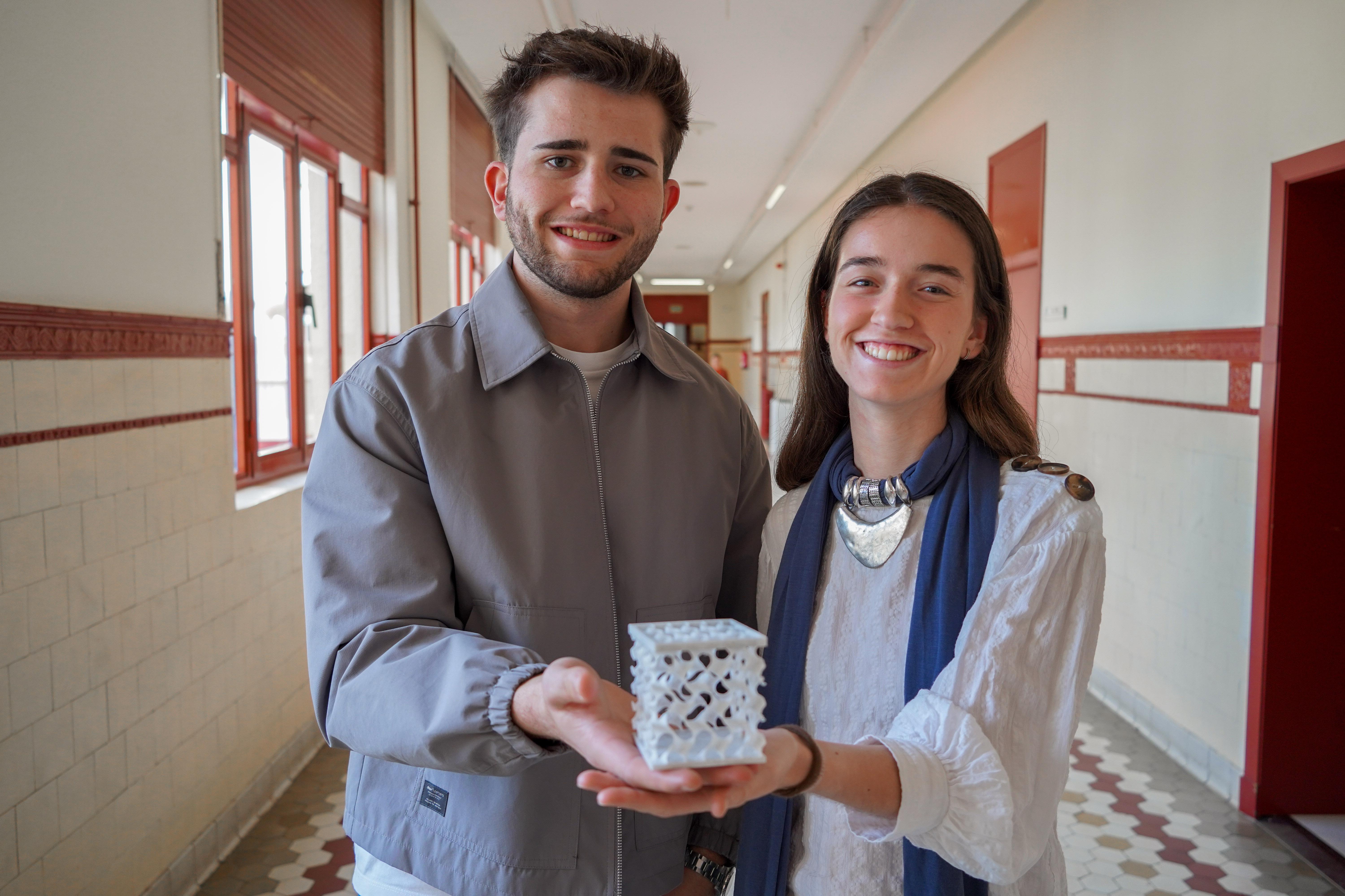 Dos jóvenes sostienen un objeto decorativo en un pasillo escolar.