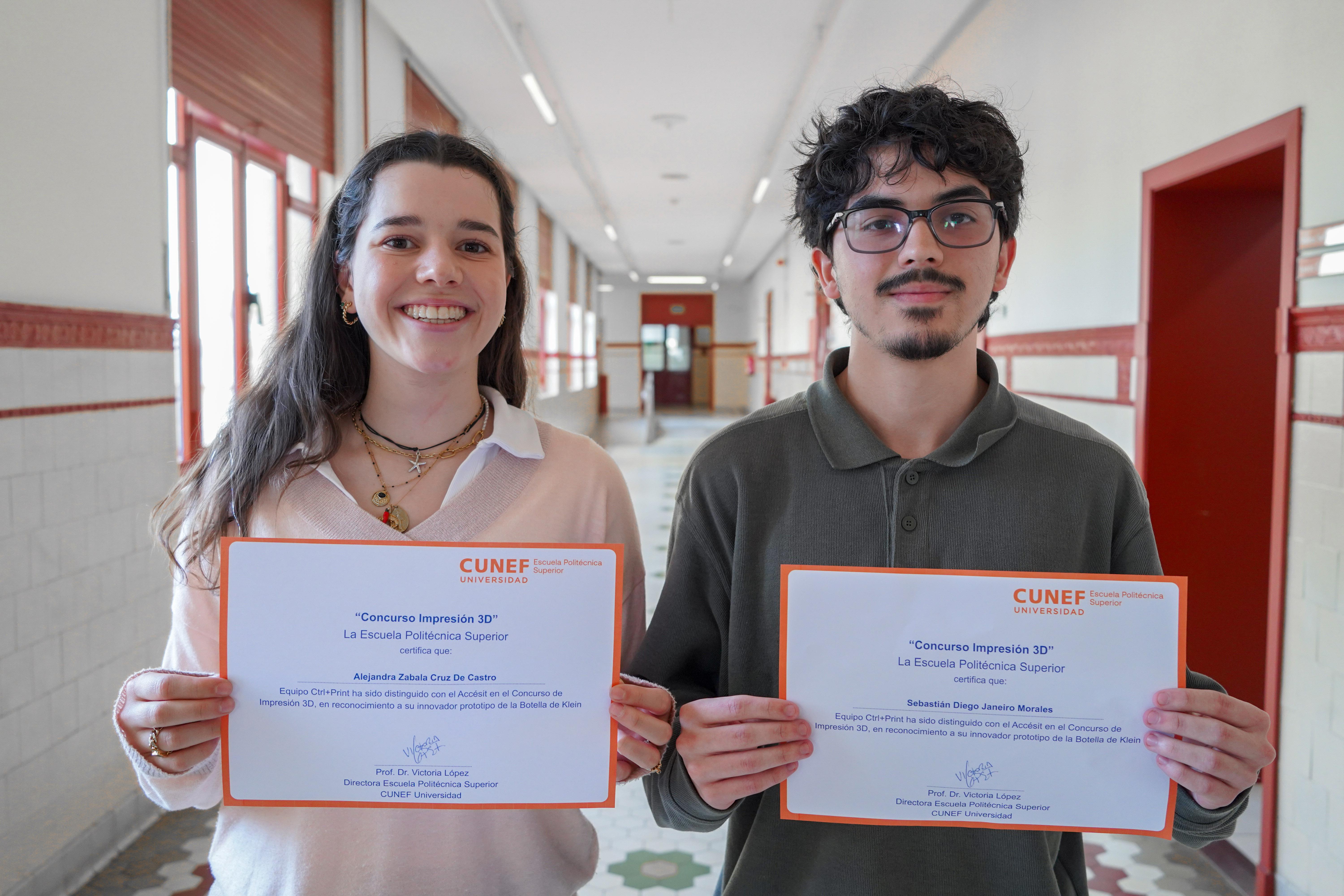Dos estudiantes sosteniendo sus certificados en un pasillo escolar.