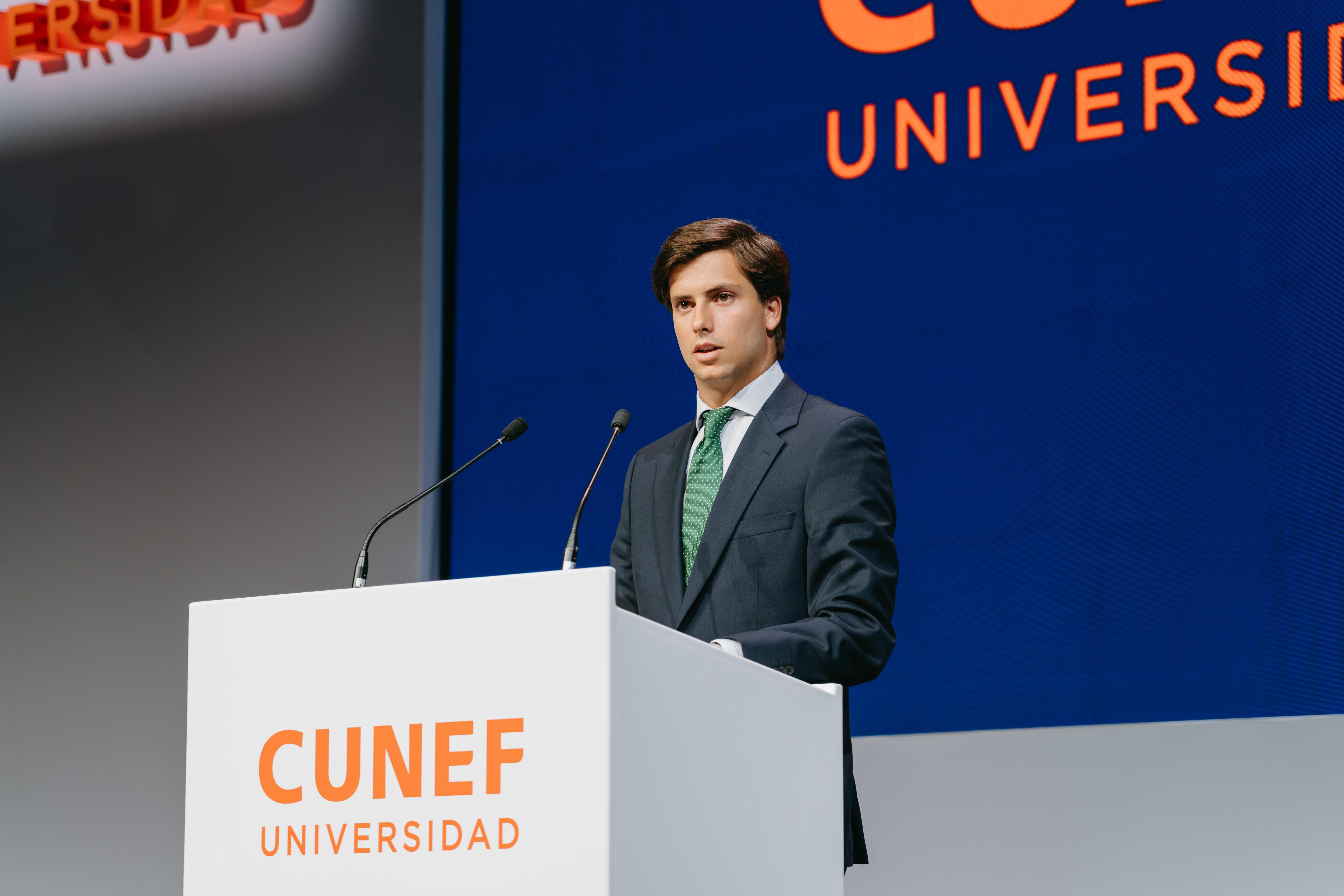 Un hombre de pie frente a un podio con el logo de CUNEF Universidad, mientras habla al público.