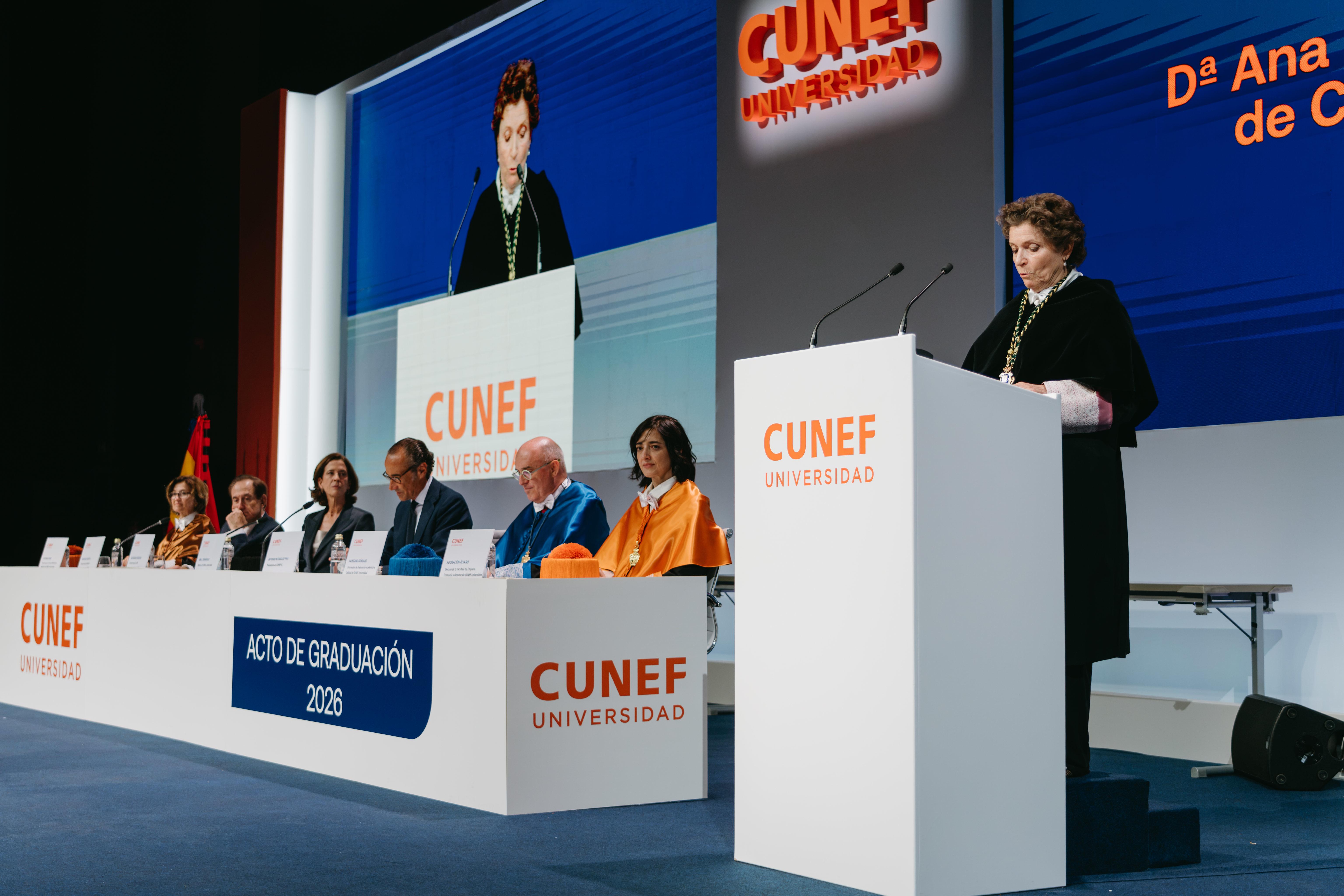 Un acto de graduación en la universidad CUNEF con varias personas en la mesa principal.