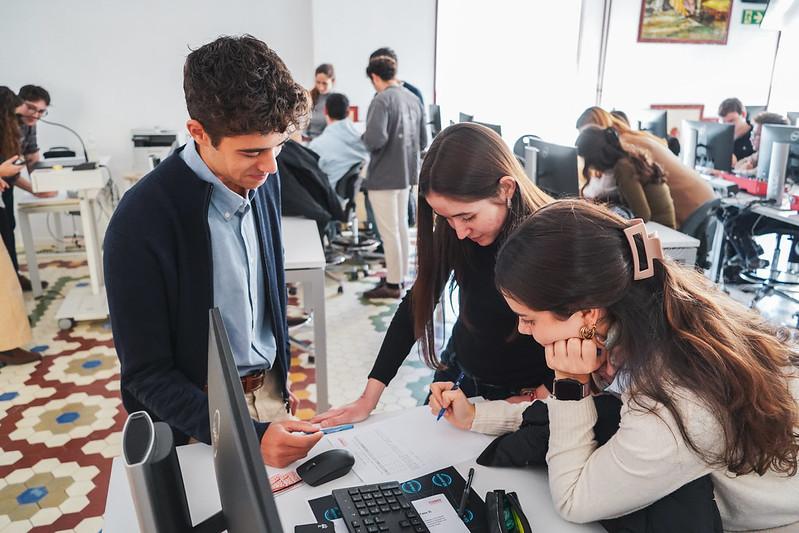 Un grupo de estudiantes colabora en una tarea frente a un escritorio en un aula.