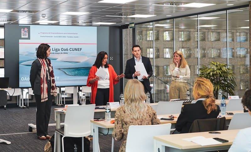 Un grupo de personas presenta en un evento corporativo con pantallas en el fondo.