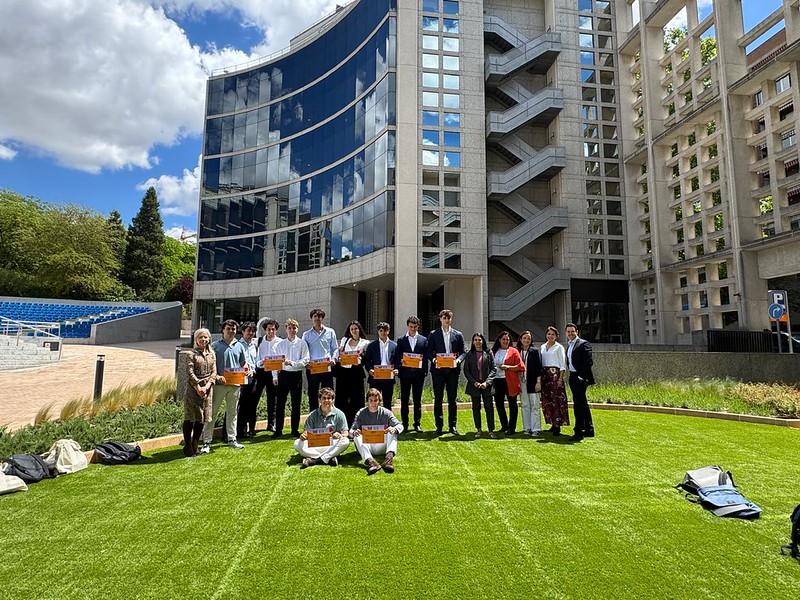Un grupo de personas se reúne en un espacio verde junto a un edificio moderno.