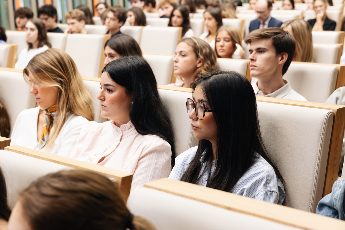 Un grupo de jóvenes sentados en un auditorio, prestando atención a un evento.