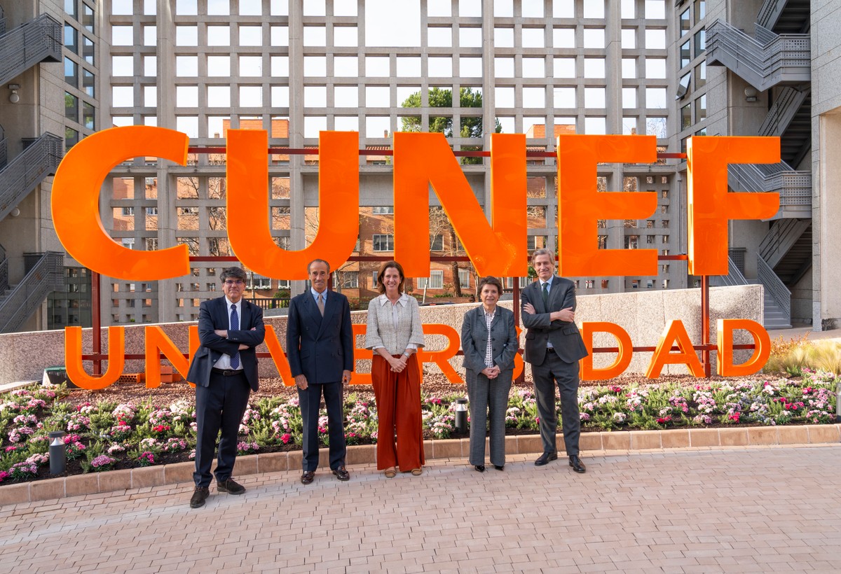 Un grupo de cinco personas posando frente a un gran letrero naranja que dice 'CUNEF UNIVERSIDAD'.