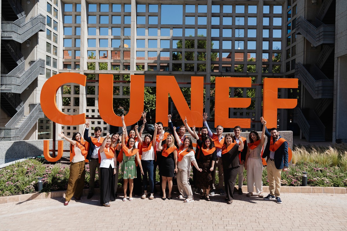 Un grupo de personas celebra frente a un gran letrero que dice 'CUNEF'.