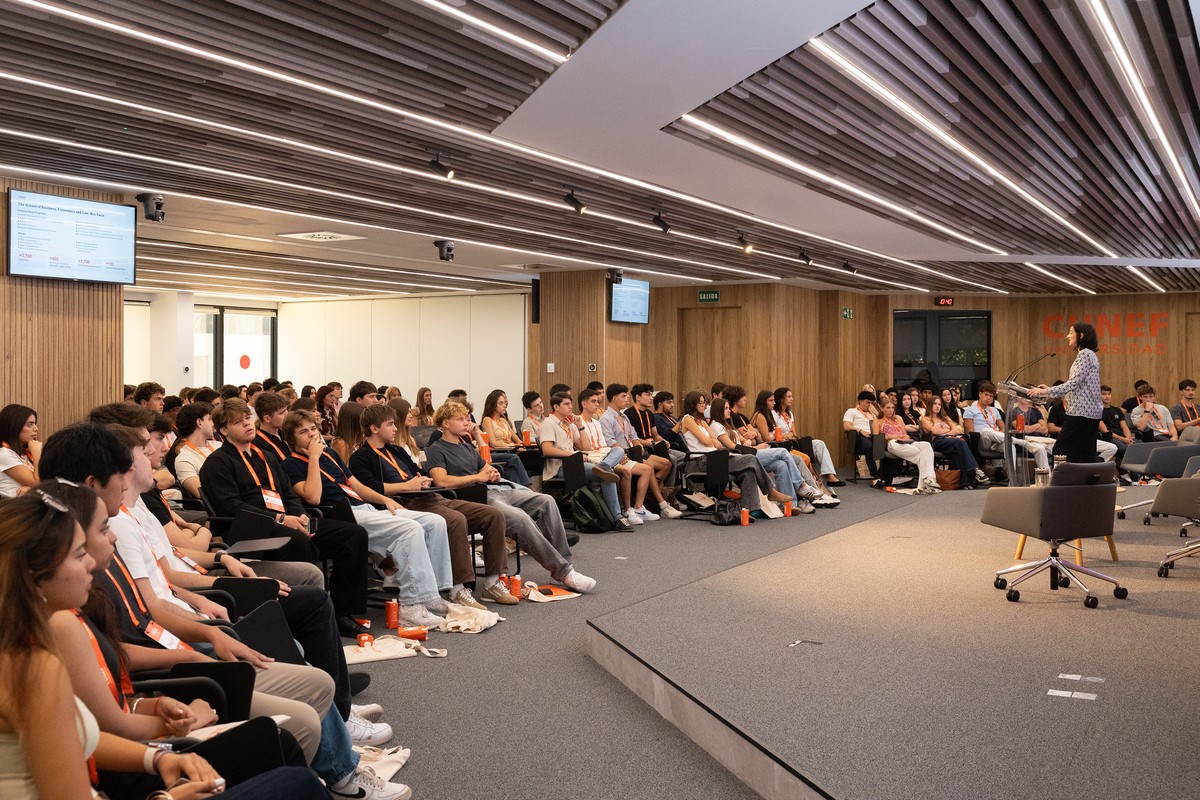Un grupo de estudiantes escucha atentamente a un ponente en un salón moderno.