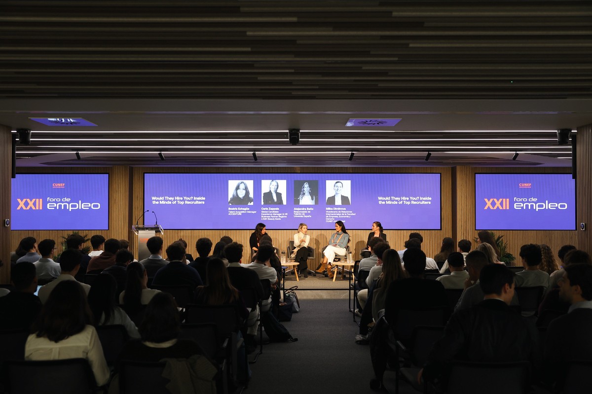 Un panel de discusión se lleva a cabo con varios ponentes frente a una audiencia en un evento sobre empleo.