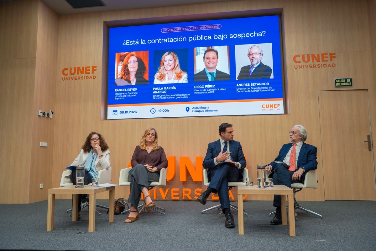 Una mesa redonda sobre la contratación pública con varios ponentes en un auditorio universitario.