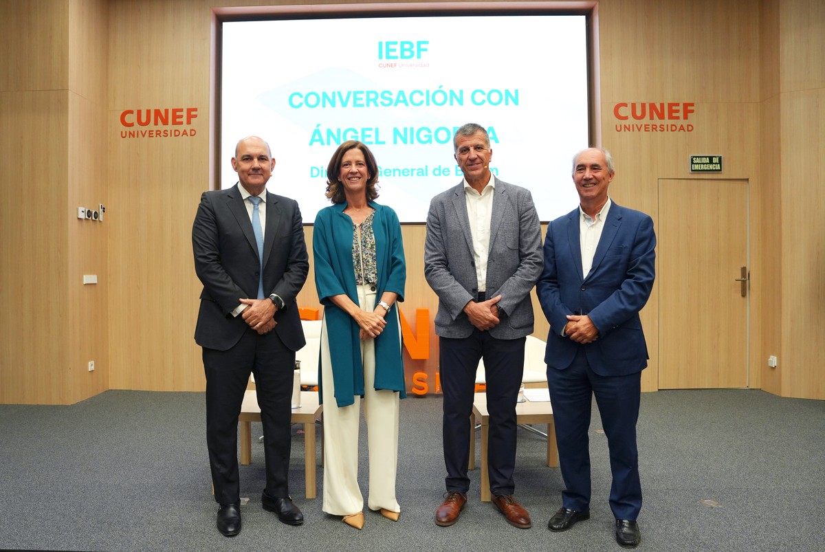 Cuatro personas posan sonrientes en un evento en la universidad CUNEF relacionado con una conversación dirigida por Ángel Nogales.
