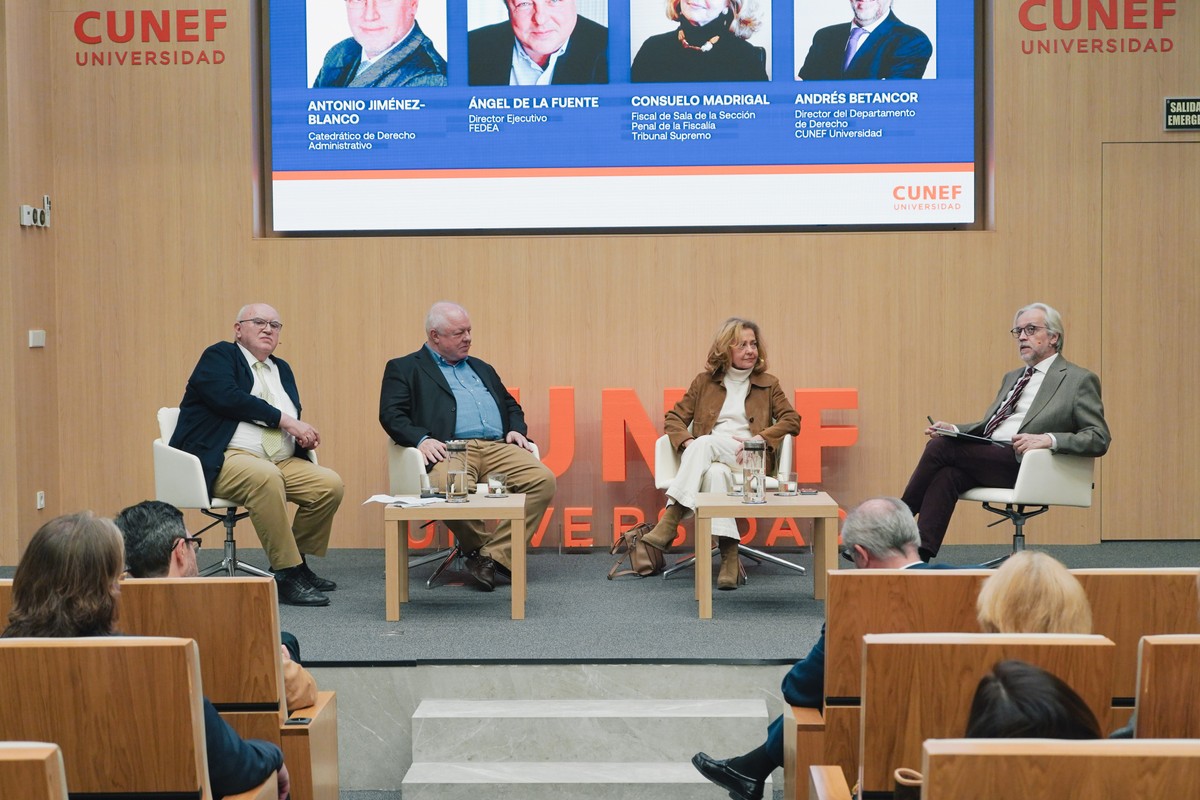 Un panel de discusión en el que participan cuatro ponentes en un auditorio universitario.