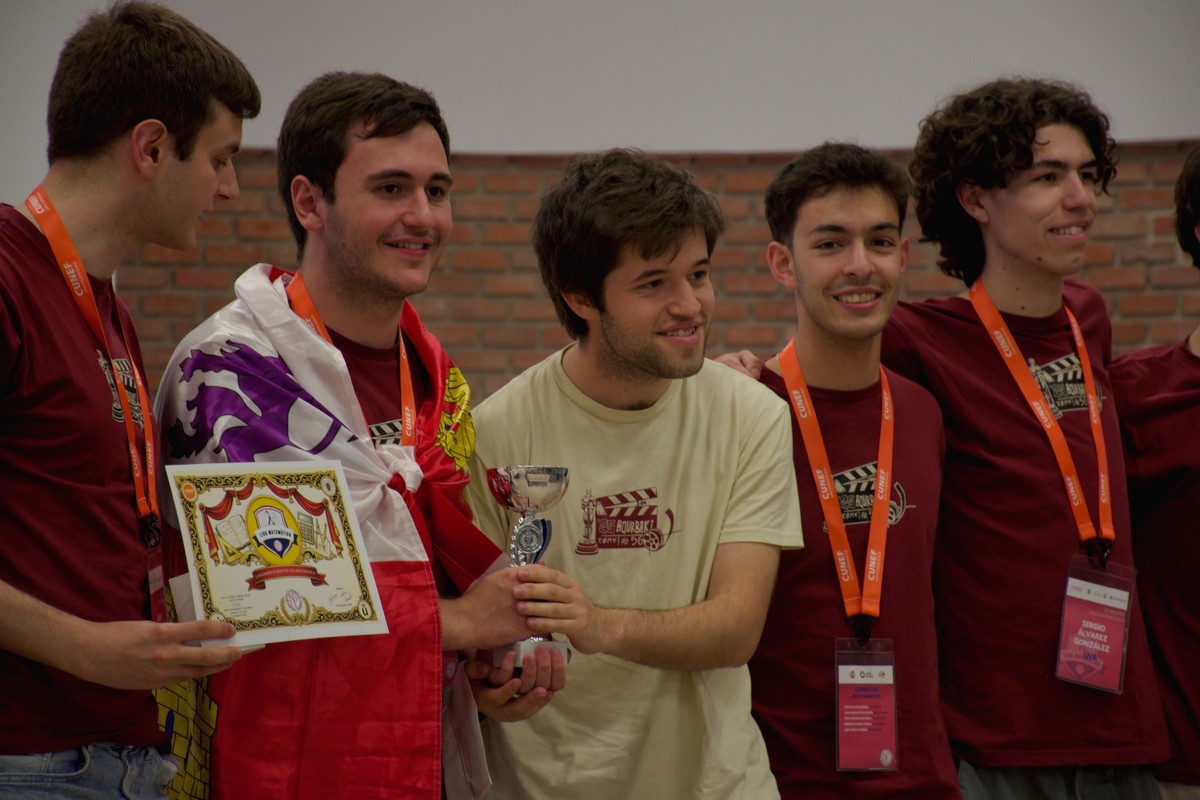 Un grupo de jóvenes celebra un reconocimiento en un evento, sosteniendo un trofeo y un diploma.