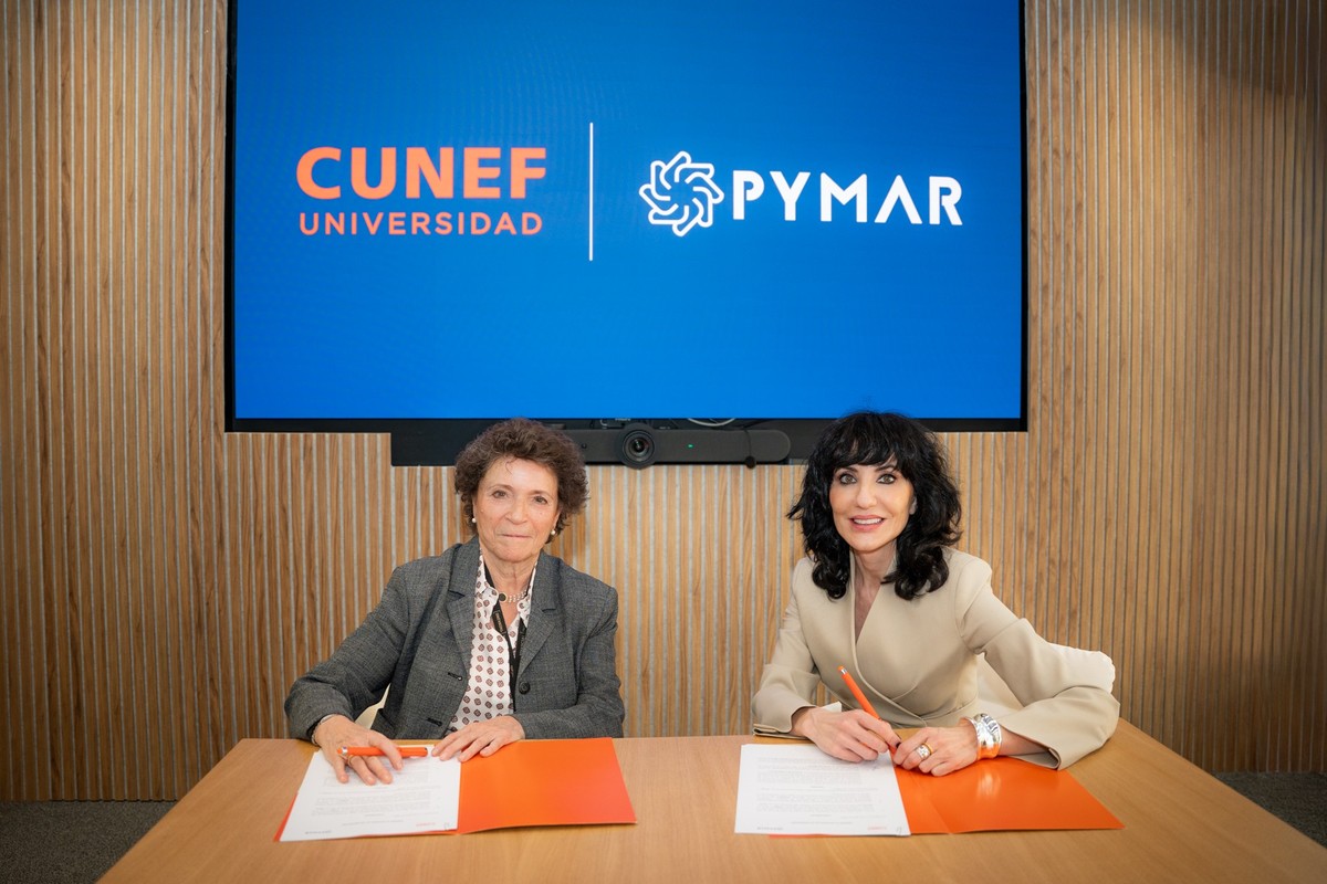 Dos mujeres están firmando un acuerdo frente a una pantalla con los logotipos de CUNEF Universidad y Pymar.