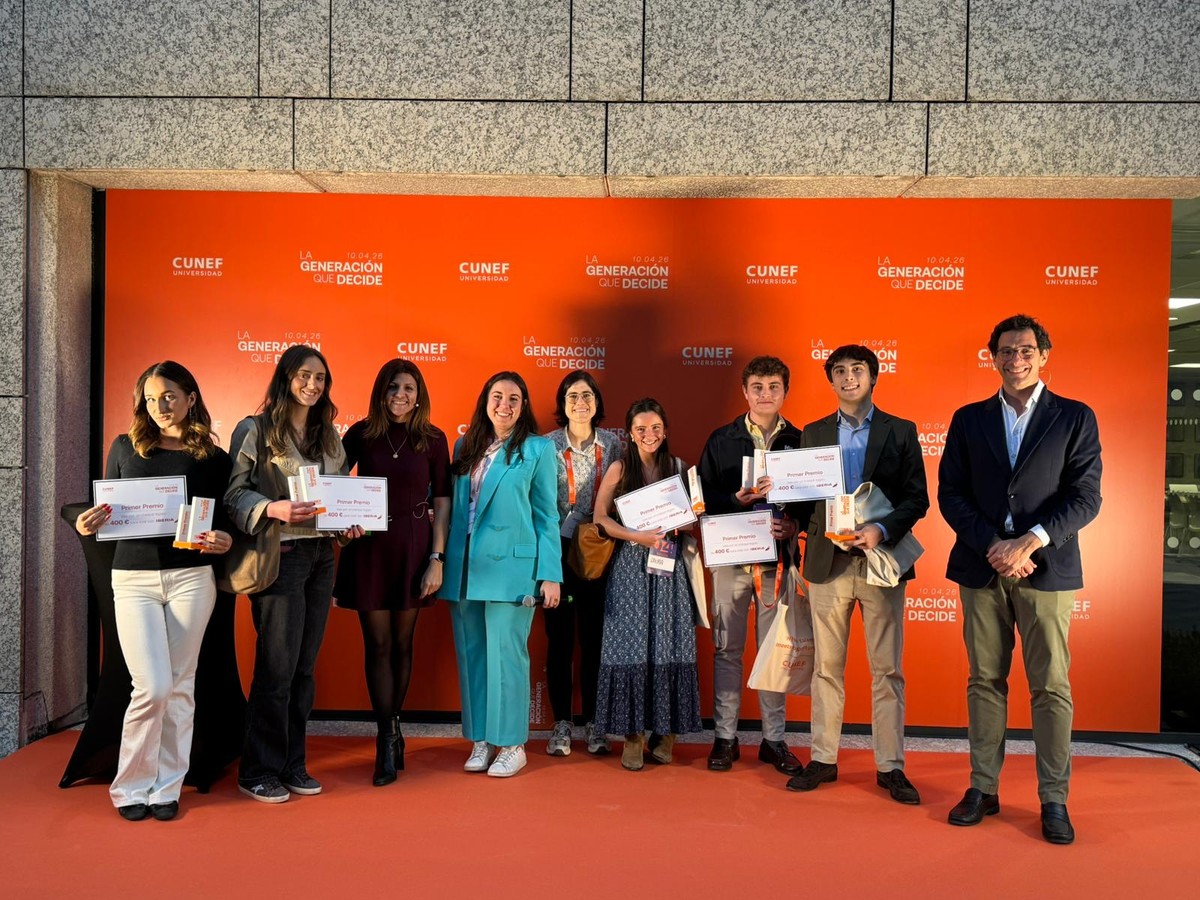 Un grupo de personas sostiene certificados frente a un fondo naranja con el logo de CUNEF.