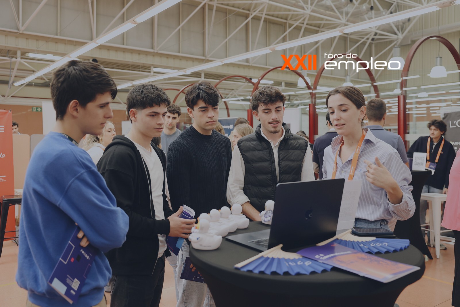 Un grupo de jóvenes interactúa con una presentadora en un foro de empleo.