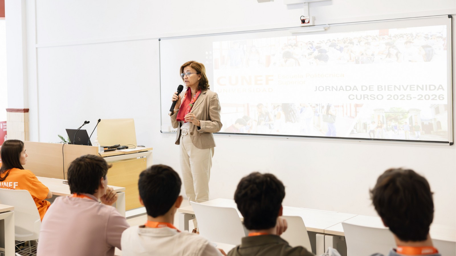 Una mujer da una charla en una jornada de bienvenida en un aula.