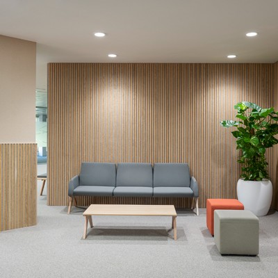 Una sala de espera moderna con un sofá gris, una mesa de madera y plantas decorativas.