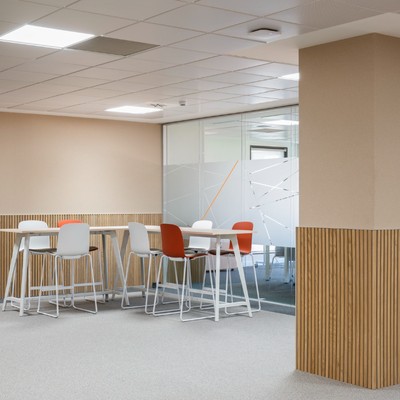 El espacio de oficina presenta mesas y sillas modernas en un ambiente luminoso y minimalista.