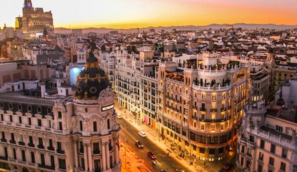 Una vista panorámica de una ciudad al atardecer con edificios y calles iluminadas.