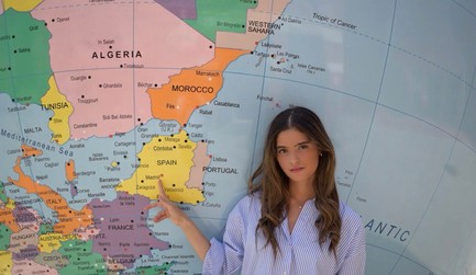 Dos estudiantes conversan y sonríen en un aula de CUNEF Universidad