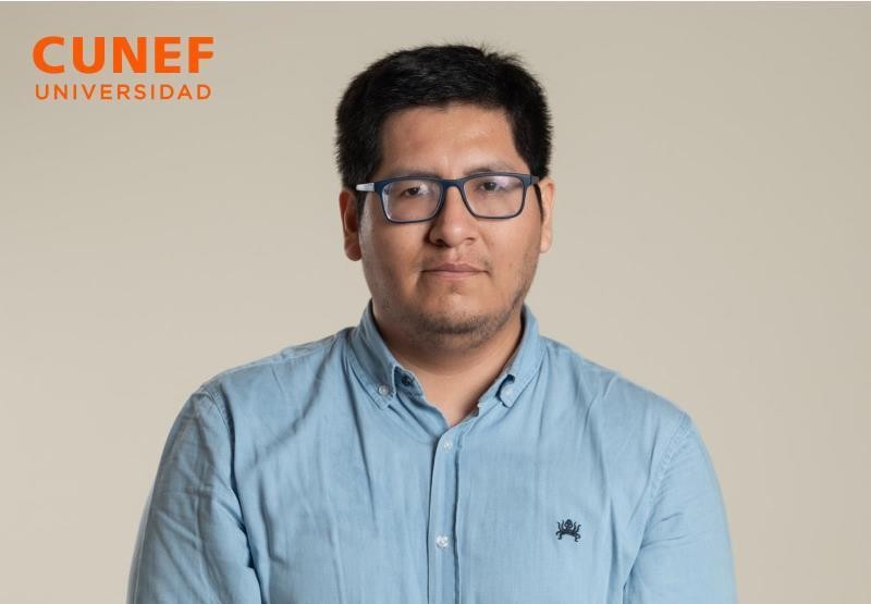 Retrato de un hombre con camisa de color claro y gafas frente a un fondo neutro.