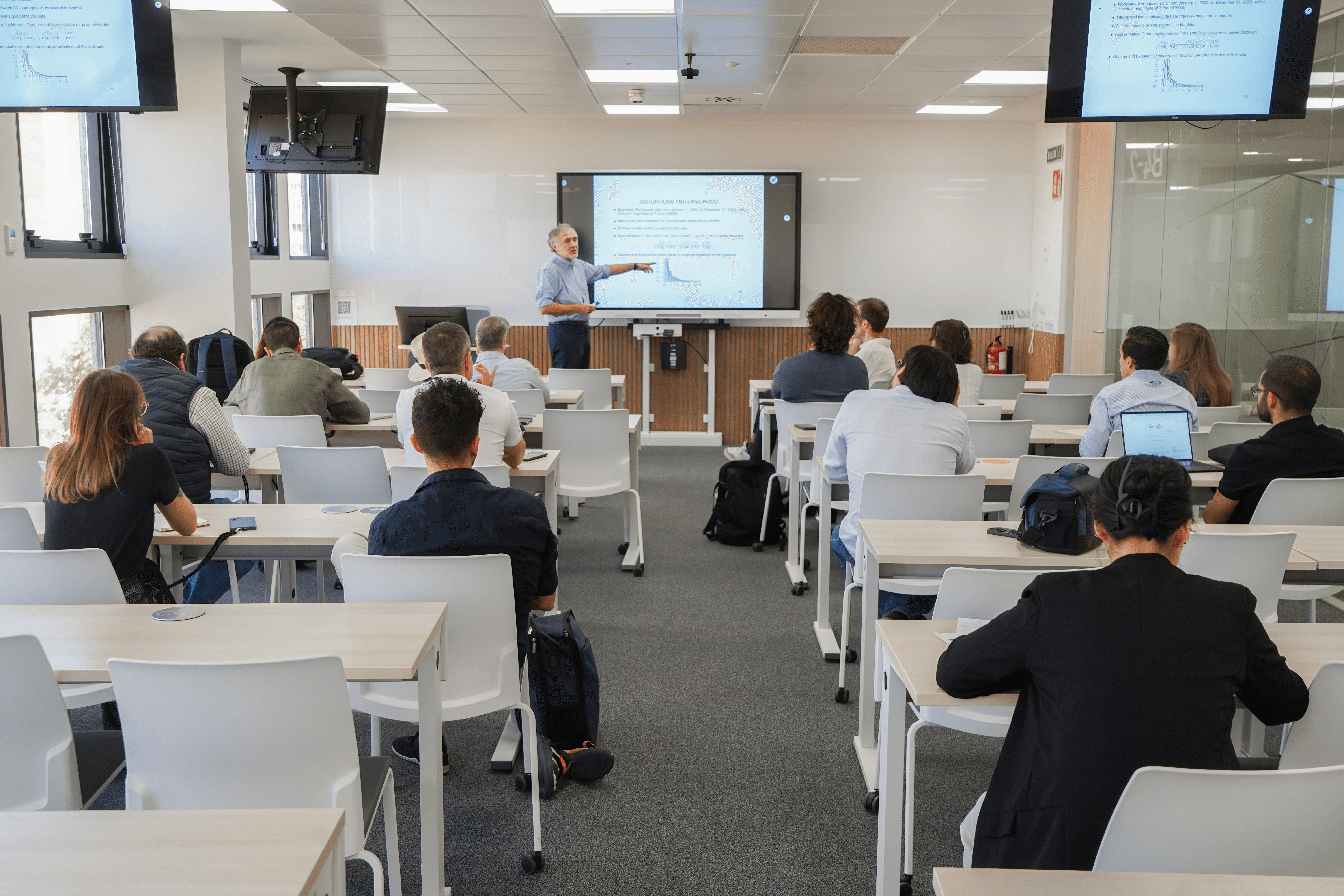 Un profesor está dando una clase a un grupo de estudiantes en un aula moderna.