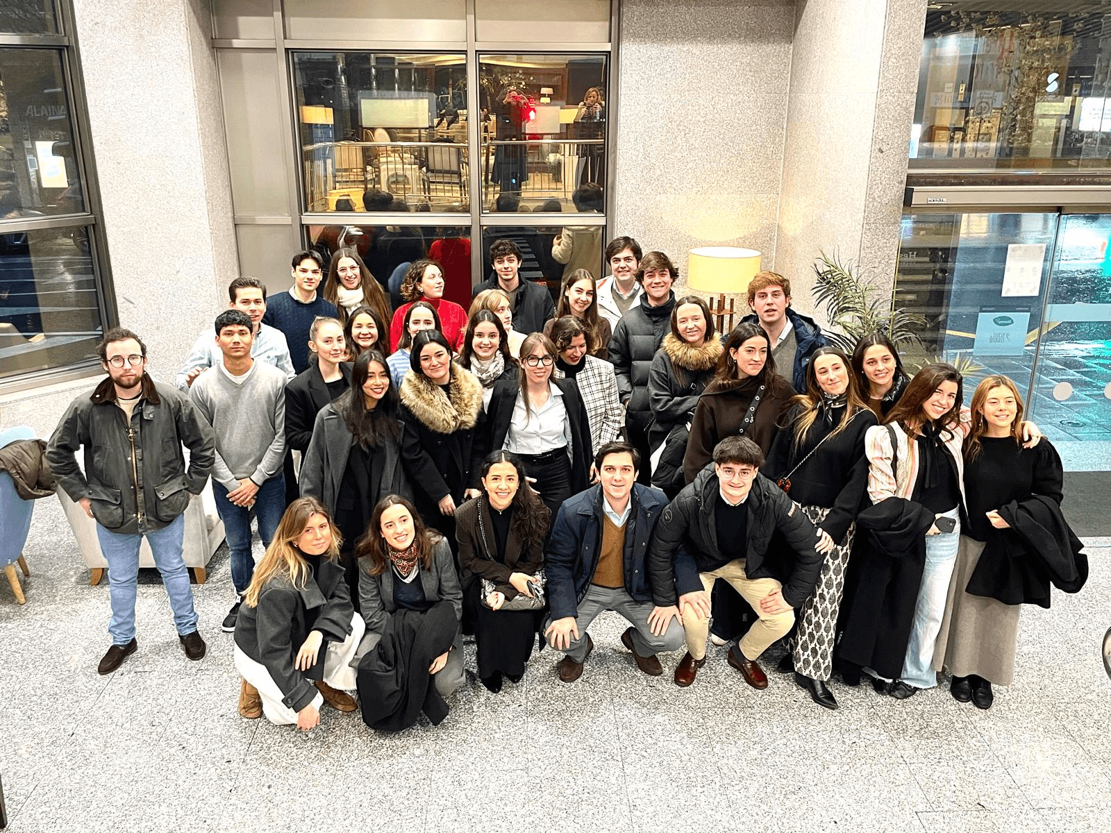 Un grupo de jóvenes se reúne en un espacio interior con luz natural y decoración moderna.